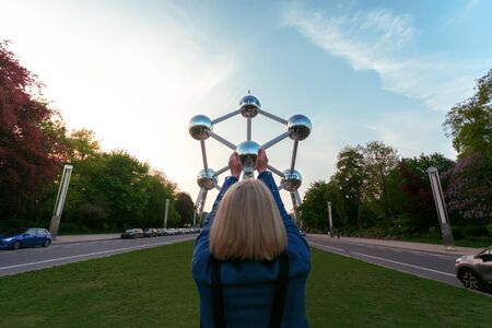 A girl is holding her hands one of the balls at the Atomium monument in Brussels, Belgium.のeditorial素材