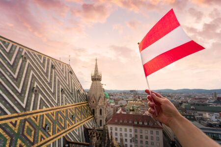 Woman holds Austria flag in hand against Vienna city panoramaの写真素材
