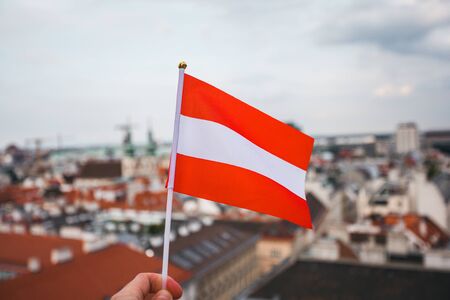 Man holds Austria flag in hand against Vienna city panorama background.の写真素材