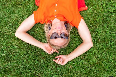 Top view of a young woman lying on the grass and smiling cute.の写真素材