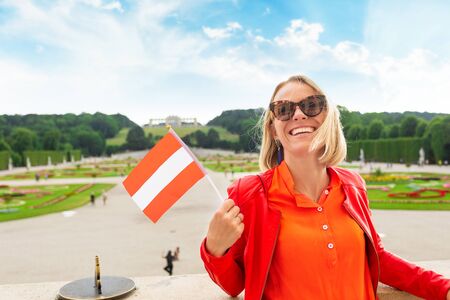 Young female tourist with the flag of Austria stands against a Schoenbrunn palace park in Vienna, Austriaのeditorial素材