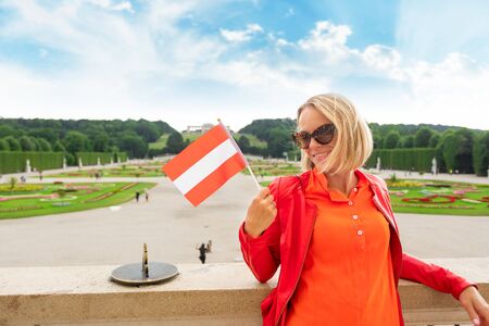 Young female tourist with the flag of Austria stands against a Schoenbrunn palace park in Vienna, Austriaのeditorial素材