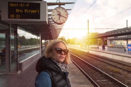 Woman tourist waiting for her train at the railway stationの写真素材