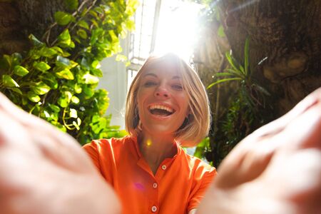 Close up shot as a girl opens her hands and is pleasantly surprised against the background of tropical greenery in the greenhouseの写真素材