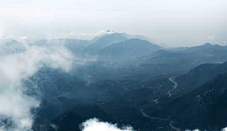 Panorama of beautiful silhouette mountains in blue tones with haze and clouds.の写真素材