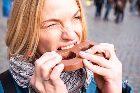 Young woman eating a chocolate bar outdoorsの写真素材