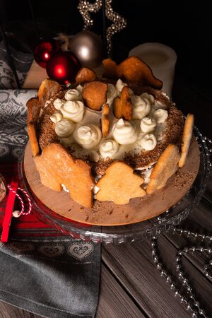 Homemade Christmas cherry cake decorated with gingerbread cookies in a New Year's entourage on a dark background. Black Forest cake with cherries and sour cream on the background of Christmas tree toys.の写真素材