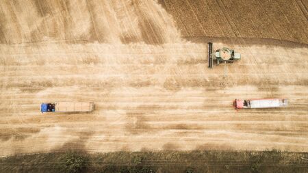 Aerial view of a combine unloads grain from grain compartment into a truckの写真素材