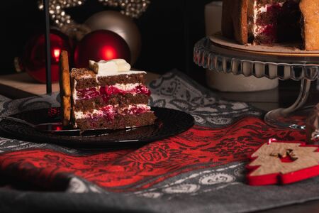 Cherry Cake Black forest on a dark background, decorated with gingerbread cookies with a cut piece on a serving plateの写真素材