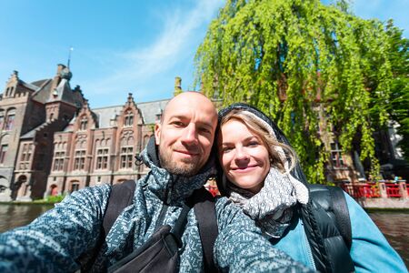 Young couple takes selfie pictures on the main street of Bruges, Belgium.の写真素材