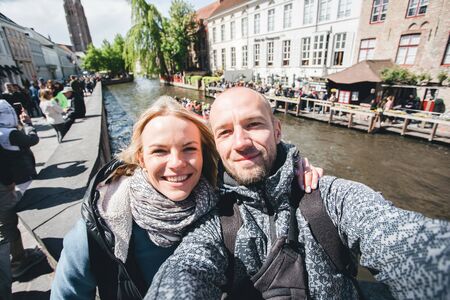 Young couple takes selfie pictures on the main street of Bruges, Belgium.の写真素材