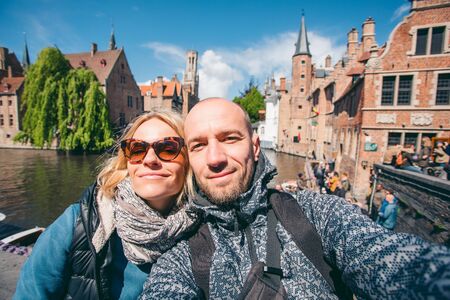 Young couple takes selfie pictures on the main street of Bruges, Belgium.の写真素材