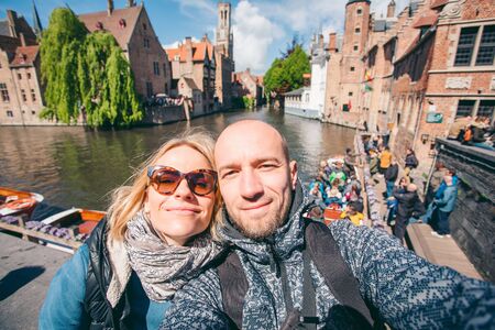 Young couple takes selfie pictures on the main street of Bruges, Belgium.の写真素材