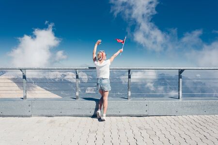 Young woman tourist stands on a viewing platform of Tahtali Mountain in Kemer with a red Turkey flag, Turkeyの写真素材