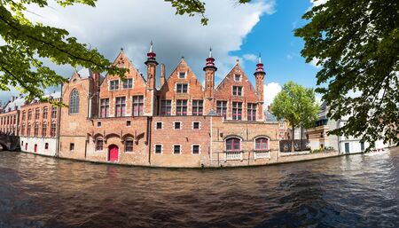 Beautiful landscape on classic houses in the Flemish style with reflection in the water of canals in the historical center of Bruges, Belgiumの写真素材