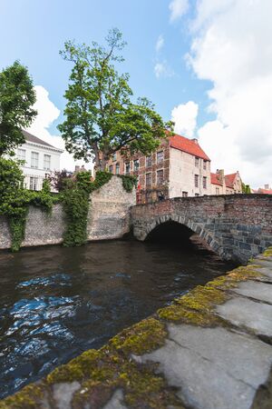 View of the canal with a bridge and houses in the classic Flemish style in the historical center of Bruges, Belgiumの写真素材