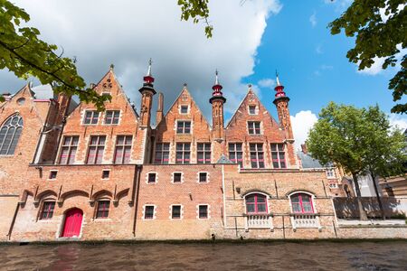 Beautiful landscape on classic houses in the Flemish style with reflection in the water of canals in the historical center of Bruges, Belgiumの写真素材