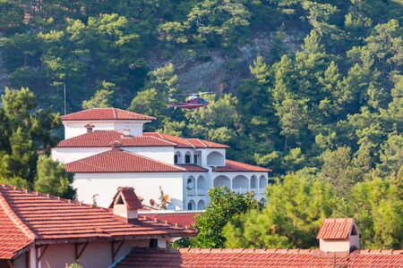 Private white building with red tiled roof in the background of nature and mountains.の写真素材
