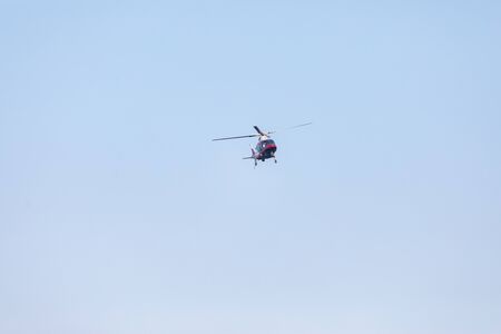 Front view of small red private helicopter against a blue sky with spinning propellersの写真素材