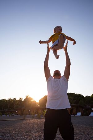 Father and son having fun on the beach at sunsetの写真素材