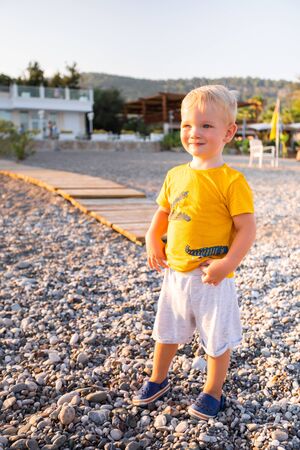 A boy stands on the beach and looks into the distance at seaの写真素材