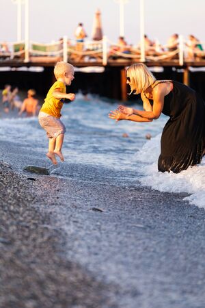 Mother and son having fun on the beach at sunsetの写真素材
