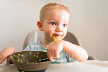 Little boy alone eats puree from a plate.の写真素材