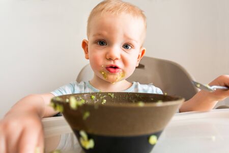 Little boy alone eats puree from a plate.の写真素材