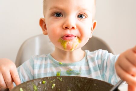Little boy alone eats puree from a plate.の写真素材