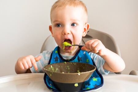 Little boy alone eats puree from a plate.の写真素材