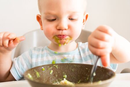 Little boy alone eats puree from a plate.の写真素材