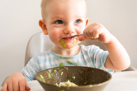 Little boy alone eats puree from a plate.の写真素材
