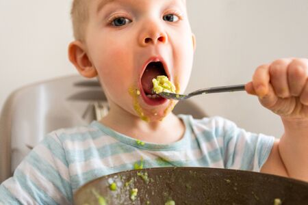 Little boy alone eats puree from a plate.の写真素材