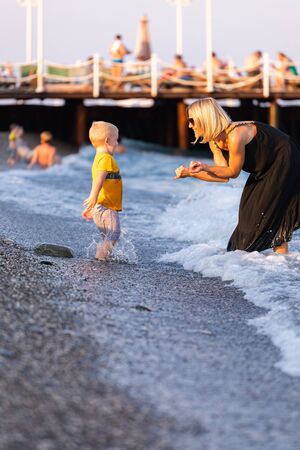 Mother and son having fun on the beach at sunsetの写真素材