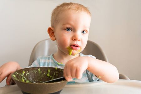 Little boy alone eats puree from a plate.の写真素材