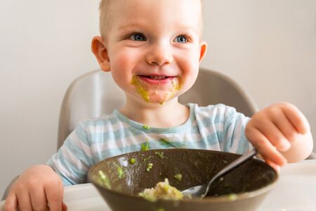 Little boy alone eats puree from a plate.の写真素材