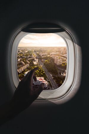 The male hand points a finger towards the aerial panorama of the city of Kiev, Ukraine, which opens from the window of the plane during the flight.の写真素材