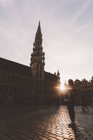 Woman stands in the square Grand Place in Brussels, Belgium at sunset.のeditorial素材