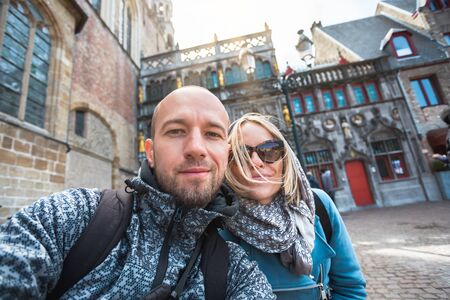 A young couple of tourists of the Basilica of the Holy Blood on Burg Square in Bruges, Belgium.の写真素材