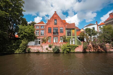 Beautiful landscape on classic houses in the Flemish style with reflection in the water of canals in the historical center of Bruges, Belgiumの写真素材