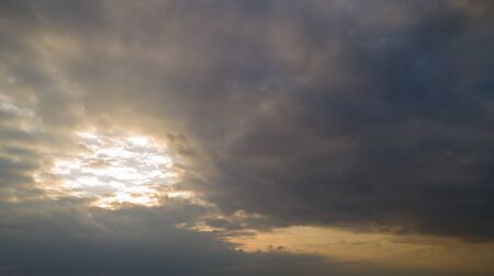 Dark cloudy sky with orange reflections at sunset.の写真素材