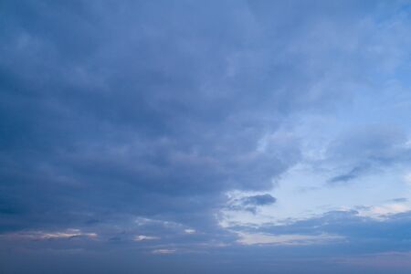 Evening blue sky with moderate clouds with a hint of orange on the horizon.の写真素材