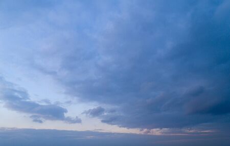 Evening blue sky with moderate clouds with a hint of orange on the horizon.の写真素材