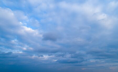 The sky covered by white clouds with glimpses of blue skyの写真素材