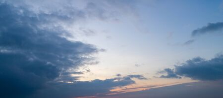 Evening blue sky with moderate clouds with a hint of orange on the horizon.の写真素材