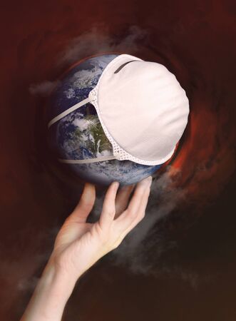 A hand holds the globe with a medical mask during an epidemic of Covid 19 or coronavirus worldwide. Conceptの写真素材