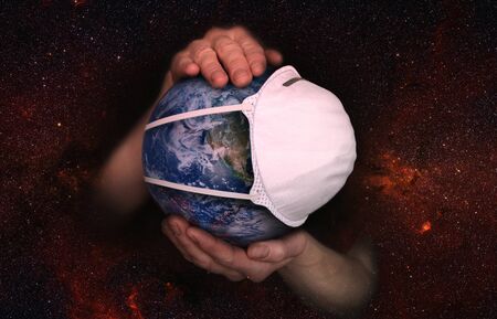 Female hands hold the Earth in a medical protective mask against the starry sky during the epidemic Covid19 or coronavirus. Conceptの写真素材