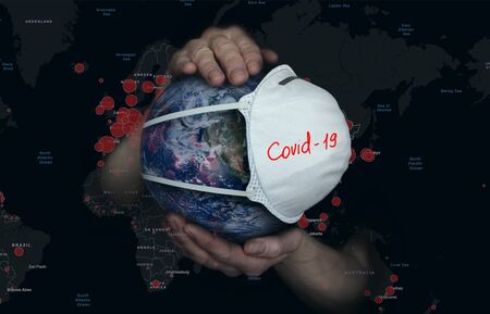 Female hands hold the Earth in a medical protective masの写真素材