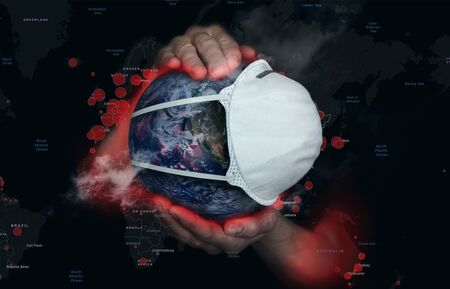 Female hands hold the Earth in a medical protective maskの写真素材