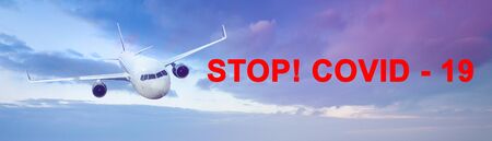 Large sky panorama with flying airplane and the inscription Stop Covid 19.の写真素材